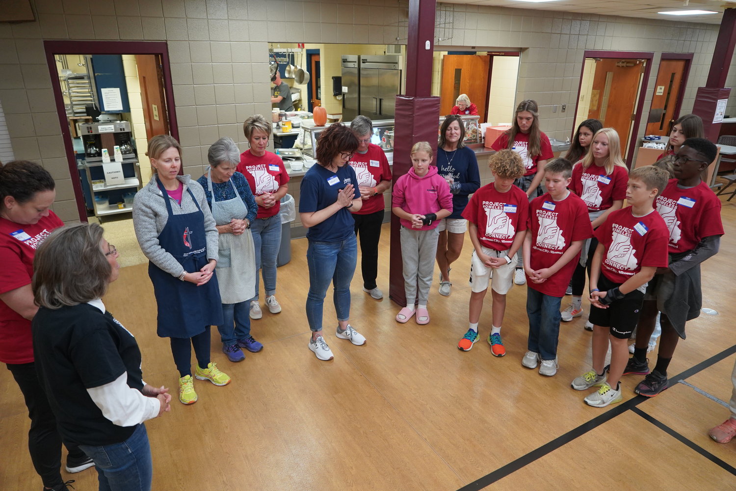 Adults from Immaculate Conception Parish and seventh-graders from Immaculate Conception School in Jefferson City gather for prayer before serving lunch and greeting visitors in the fellowship hall of First United Methodist Church during Project Homeless Connect in Jefferson City.